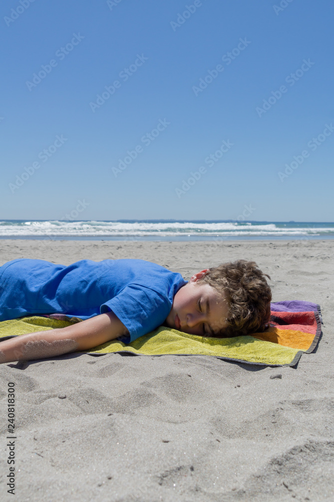 Boy lying on towel on beach