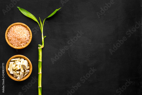 Asian spa treatments with natural ingredients concept. Bamboo branch, spa cosmetics on black background top view copy space