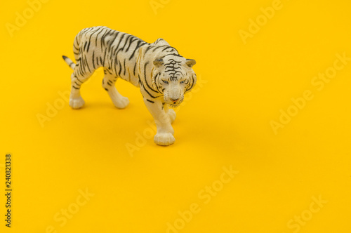 White albino tiger toy made of plastic on a yellow background.