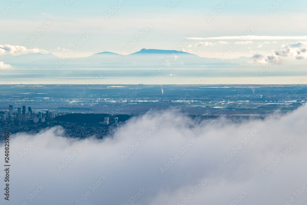 view of downtown behind cloud from high point with mist covered mountain range in the background