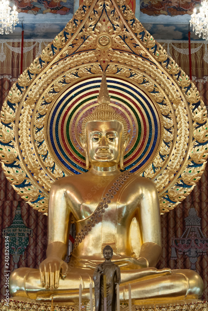 Golden buddha statue sitting in sanctuary at temple in Bangkok, Thailand.