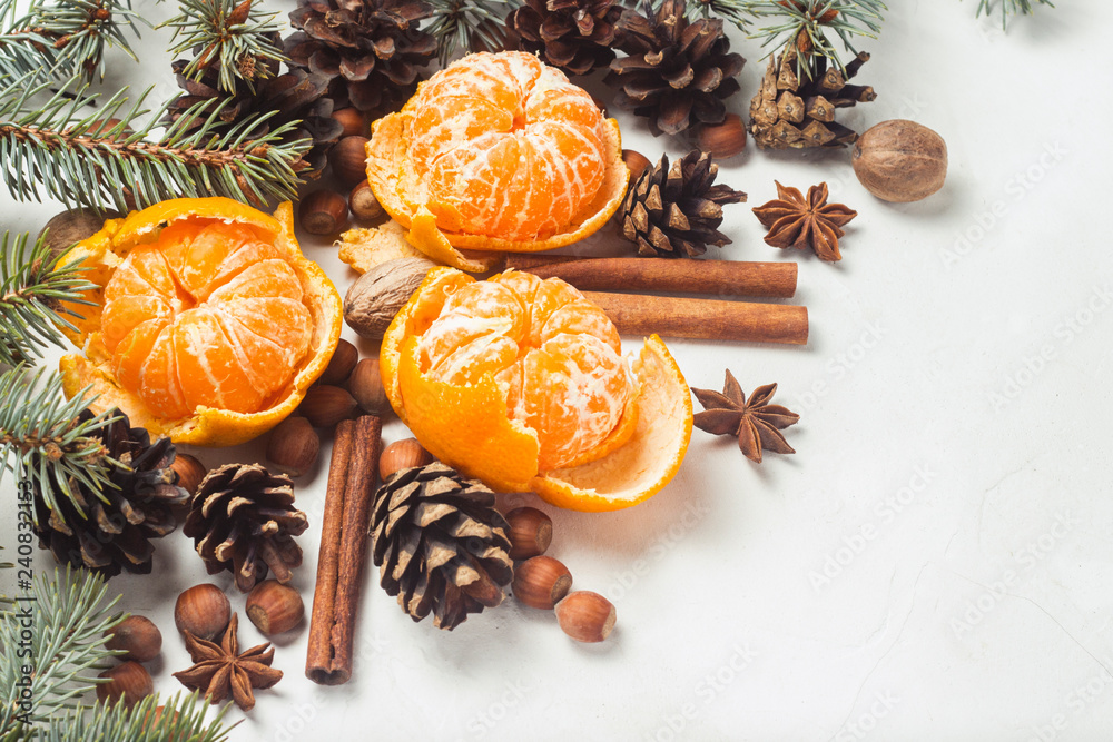 Fototapeta premium Tangerines without peel, Christmas tree branches, spices, cinnamon, cones on a white stone background. Concept of Christmas, New Year, Mulled Wine