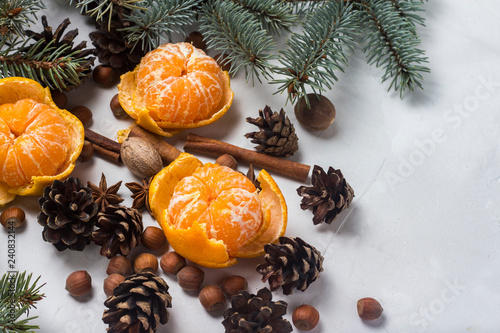 Tangerines without peel, Christmas tree branches, spices, cinnamon, cones on a white stone background. Concept of Christmas, New Year, Mulled Wine