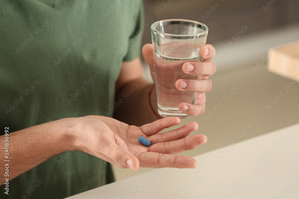 Young man with pill and glass of water indoors, closeup Young man with pill and glass of water indoors, closeup