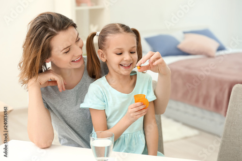 Young mother giving pill to...
