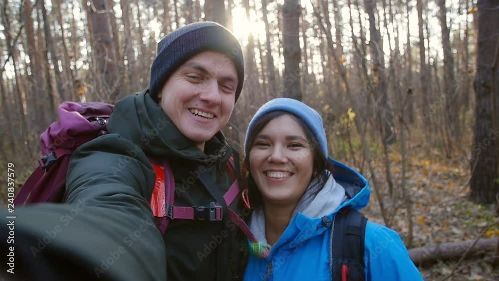 Hiking and Backpacking concept. Young happy couple with backpacks in the forest and making selfie