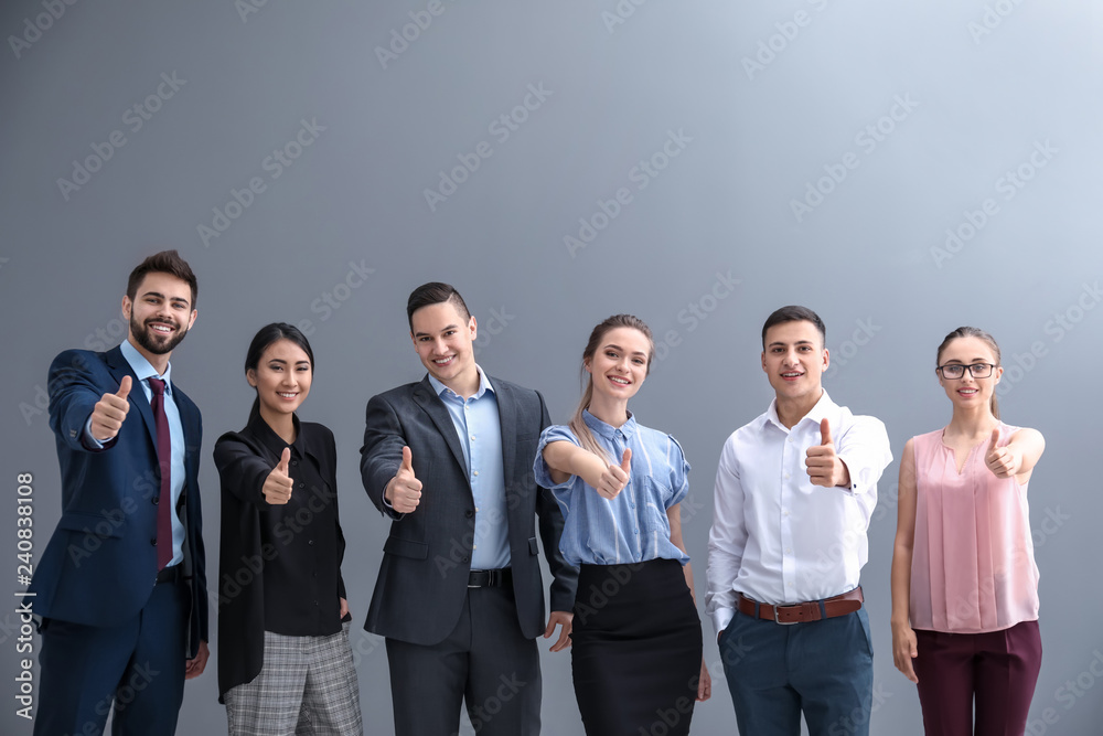 Young people showing thumb-up gesture on grey background Young people showing thumb-up gesture on grey background