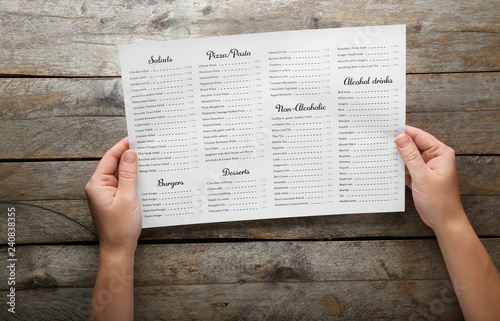 Female hands with menu on wooden table photo