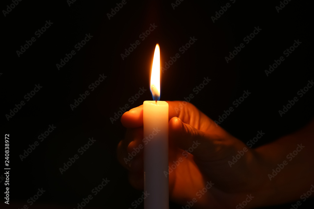Female hand with burning candle in darkness Female hand with burning candle in darkness