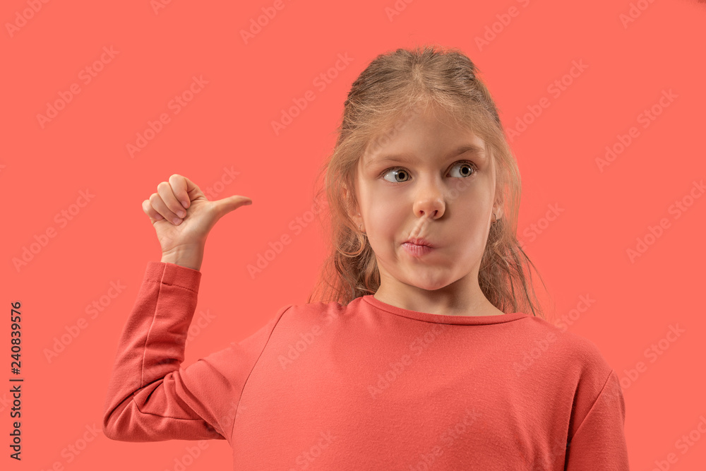 Cute happy little surprised girl in coral dress with long hair pointing back at studio. Human emotions and facial expression over trendy color Cute happy little surprised girl in coral dress with long hair pointing back at studio. Human emotions and facial expression over trendy color