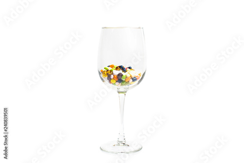 Wine glass with a lot of multicolored pills, tablets and capsules, isolated on the white background with copy space