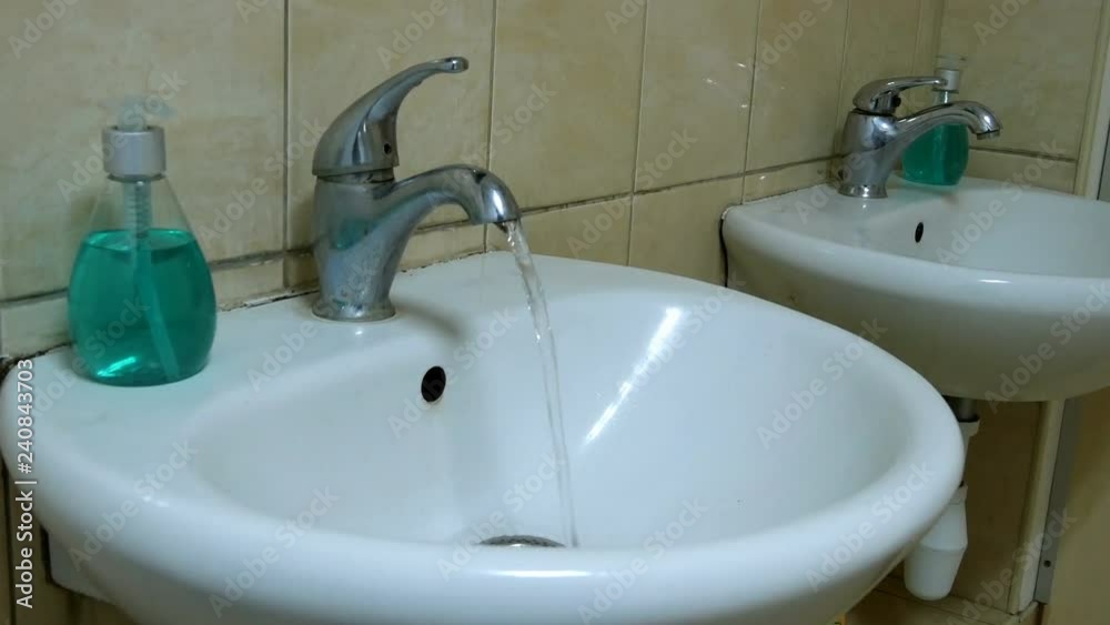 Clean water flows from the dirty tap. Running water. Representing water wastage. Color flashes blink. Clean water flows from the dirty tap. Running water. Representing water wastage. Color flashes blink.