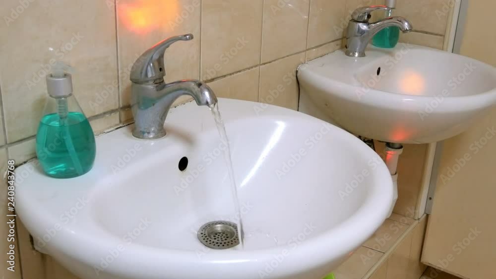 Clean water flows from the dirty tap. Running water. Representing water wastage. Color flashes blink. Clean water flows from the dirty tap. Running water. Representing water wastage. Color flashes blink.
