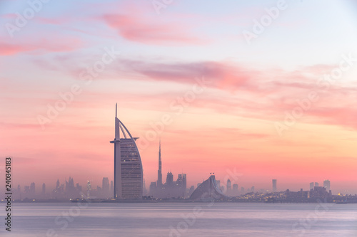 Платно Stunning view of Dubai skyline from Jumeirah beach to Downtown lighted with warm pastel sunrise colors