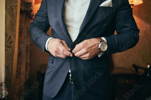 Businessman wears a jacket male hands closeup groom getting ready in the morning before wedding ceremony