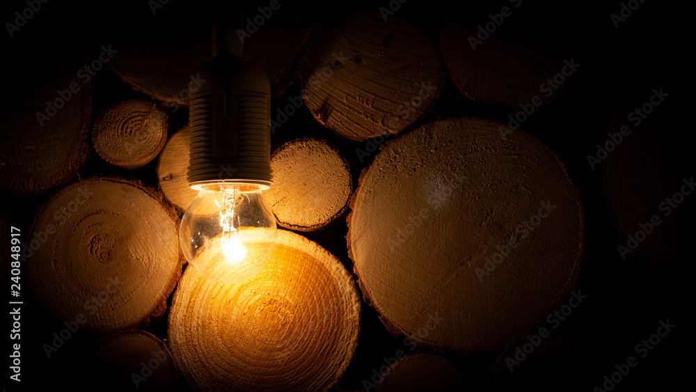 Dim light bulb on the background of a wooden log wall background Stock  Photo | Adobe Stock