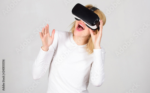 A person in virtual glasses flies in room space. Woman using VR device. Person with virtual reality helmet isolated on grey background. Game VR.