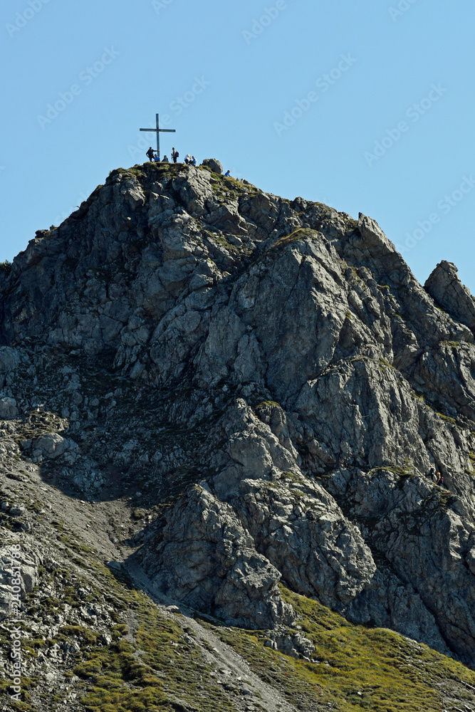 Fototapeta premium personen am gipfelkreuz der kanzelwand im kleinwalsertal