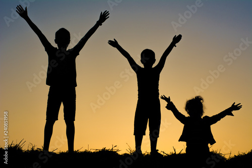 silhouette of family on sunset background of blue sky