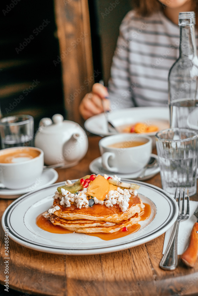 Perfect breakfast in the city cafe with pankakes, oatmeal, coffe and tea on the round wooden table. Perfect breakfast in the city cafe with pankakes, oatmeal, coffe and tea on the round wooden table.