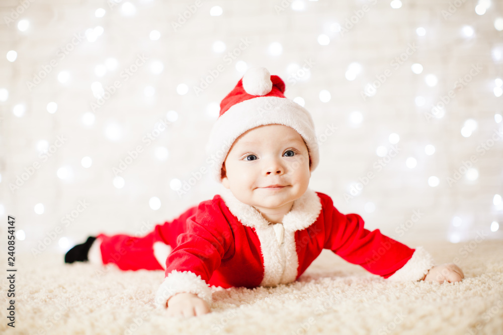 Little Santa baby over white defocused lights Little Santa baby over white defocused lights