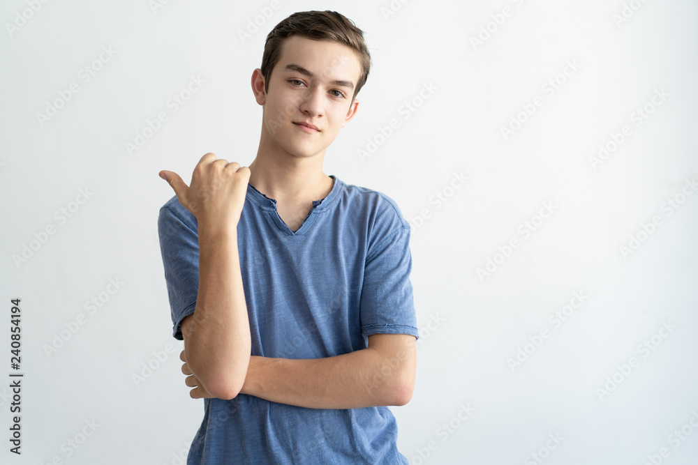 Satisfied teenage guy advertising product, service, offer. Young man pointing finger at copy space away. Advertising or presentation concept Satisfied teenage guy advertising product, service, offer. Young man pointing finger at copy space away. Advertising or presentation concept