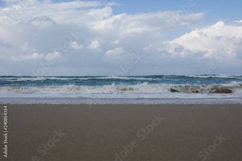 Waves crashing on shoreline with moody dramatic sky