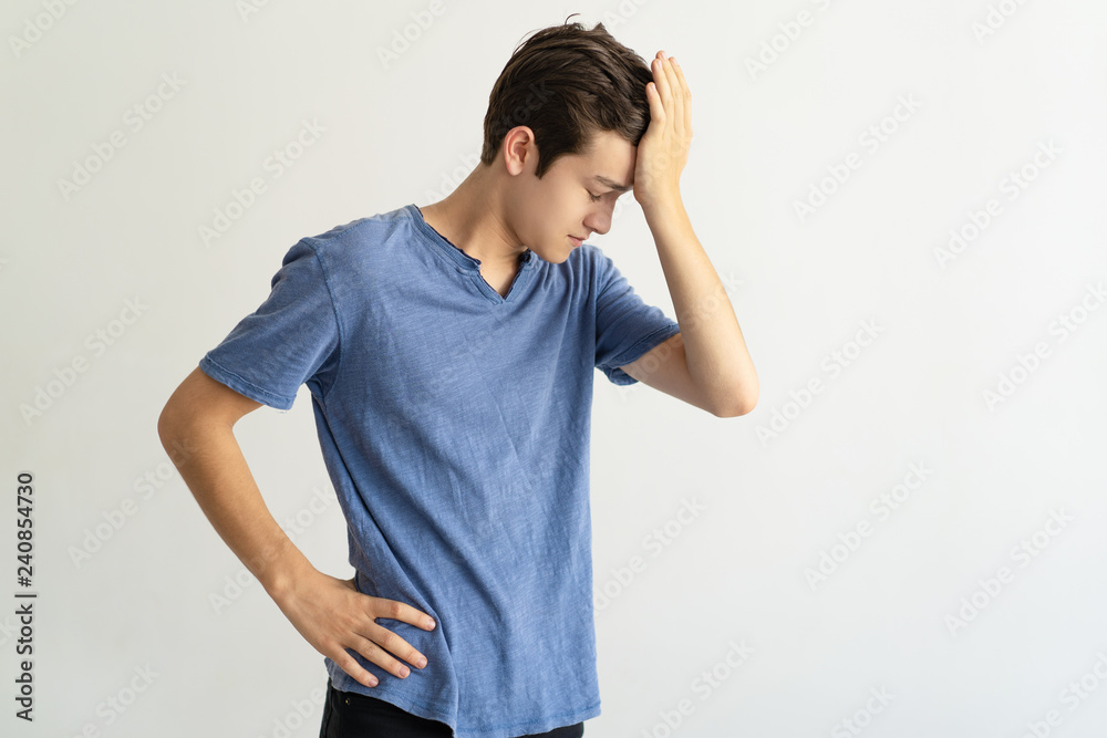 Puzzled young man holding forehead while feeling stress. Frustrated guy in blue tshirt having problem. Failure concept Puzzled young man holding forehead while feeling stress. Frustrated guy in blue tshirt having problem. Failure concept