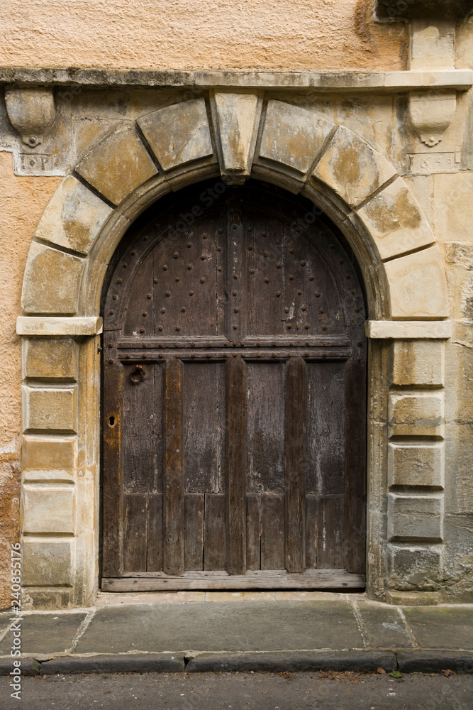 An ancient studded wood entrance door on a street in Cirencester, Gloucestershire, UK
