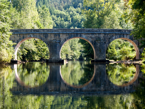 .Symetrical reflection of an old road bridge in the River Cele near Sauliac sur Cele, Lot, Midi Pyrenees, France, Europe photo