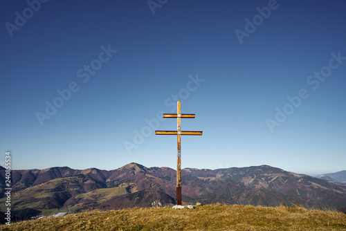 Double cross on a hill with mountain background on sunny day without clouds