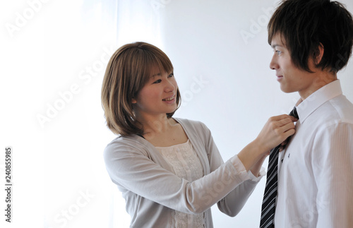 夫のネクタイを締める若い妻