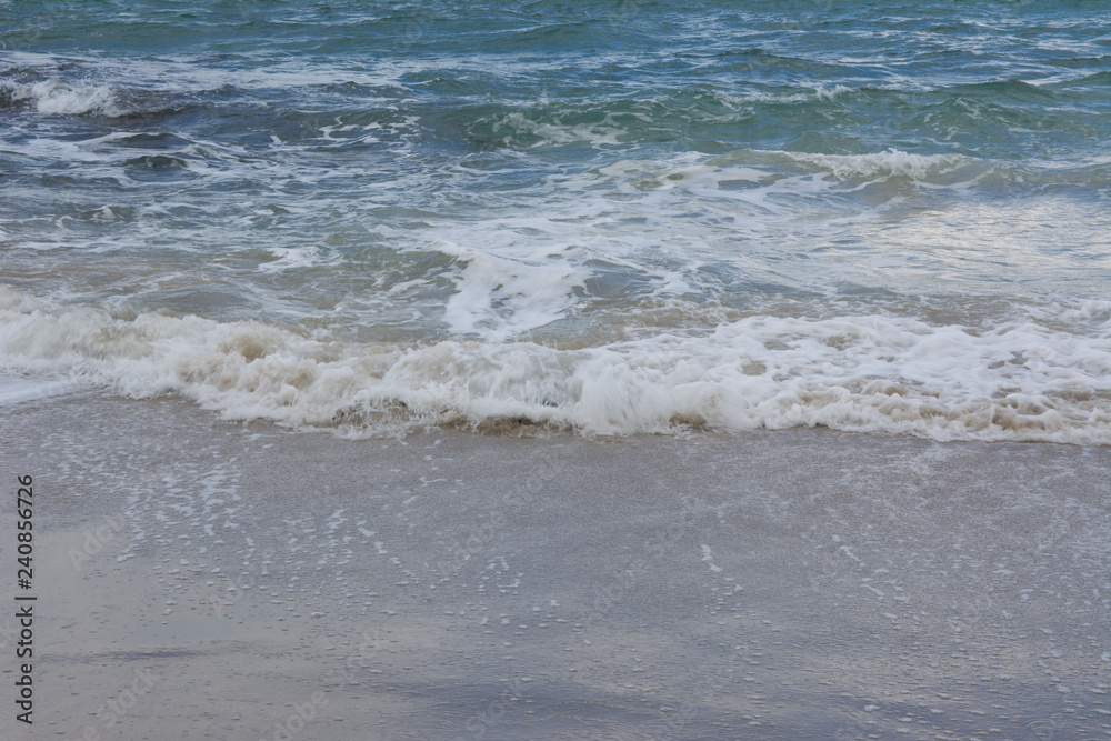 Waves crashing on shoreline with moody dramatic sky