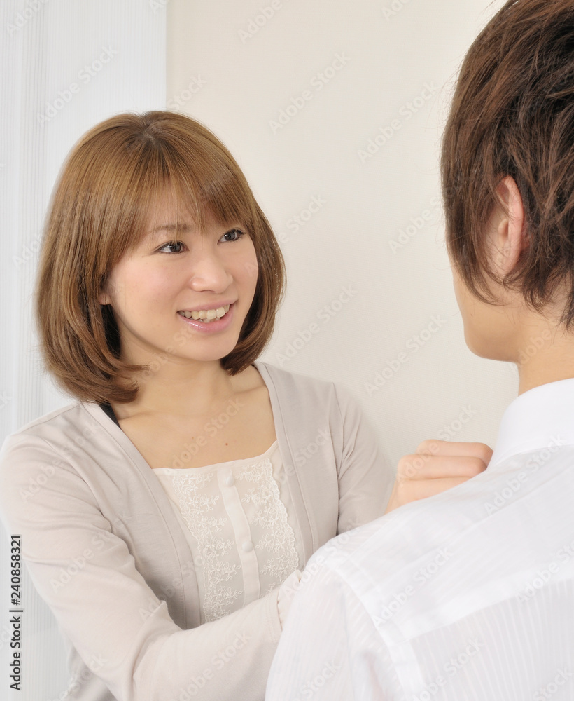 夫のネクタイを締める若い妻 夫のネクタイを締める若い妻