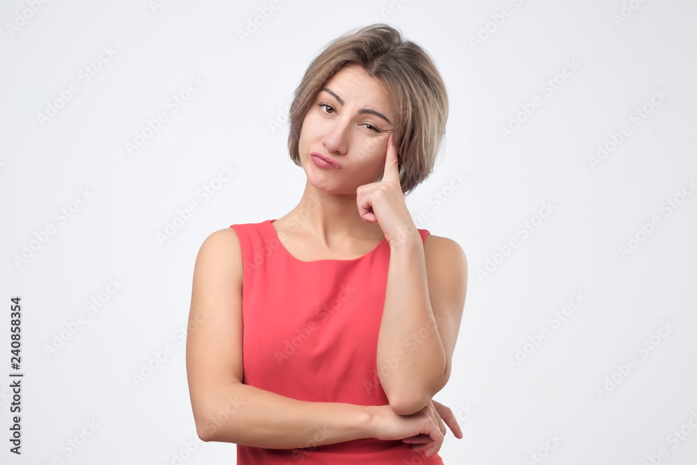 Serious young female wearing red dress looking at camera, her eyes full of distrust and disappoinment as she has quarrel with boyfriend. Studio shoot. Serious young female wearing red dress looking at camera, her eyes full of distrust and disappoinment as she has quarrel with boyfriend. Studio shoot.