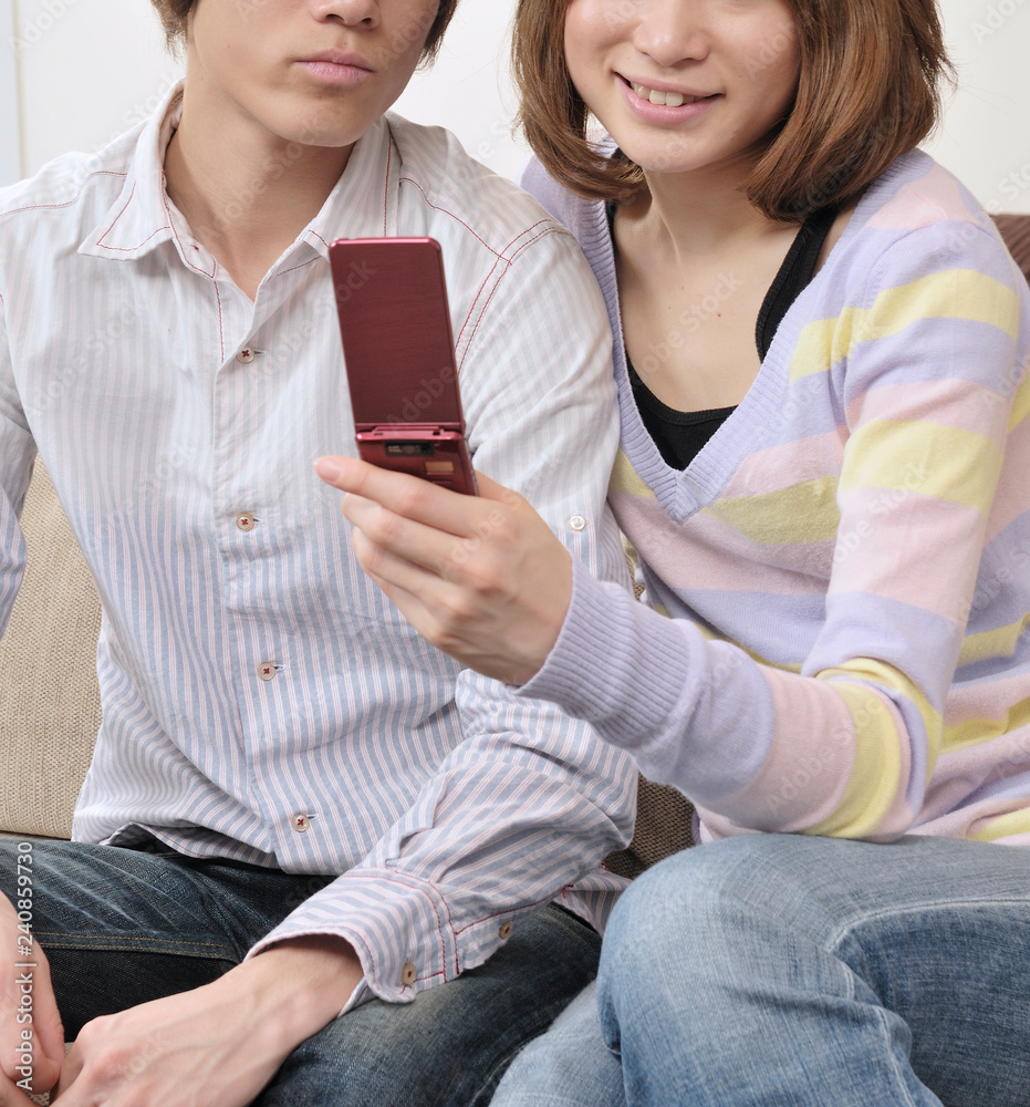 ソファに座ってガラケーを見るカップル Stock Photo Adobe Stock