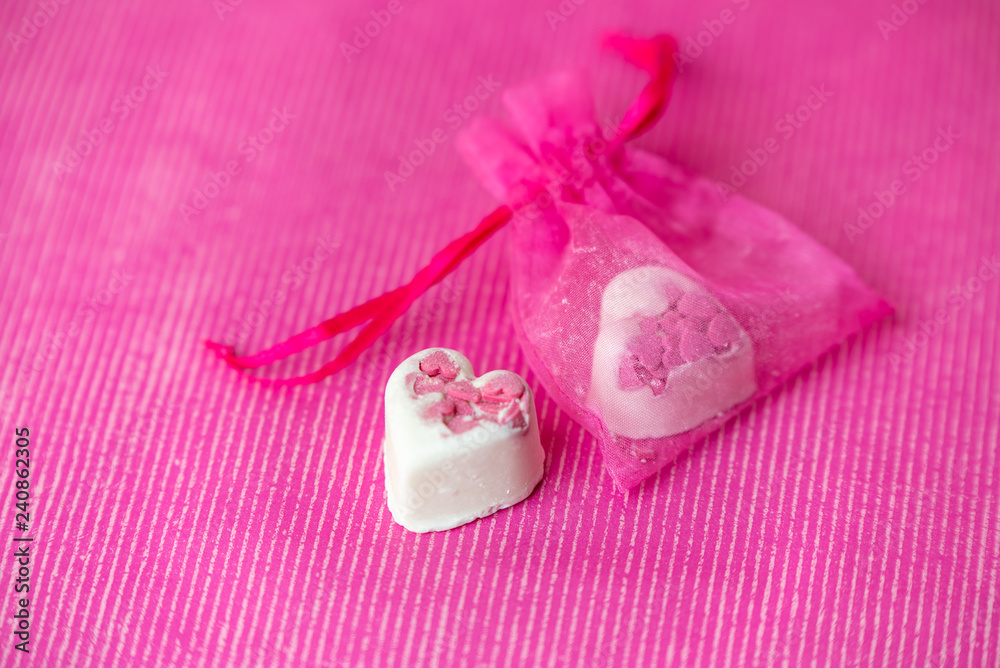 sweet white heart-shaped chocolates on a pink background