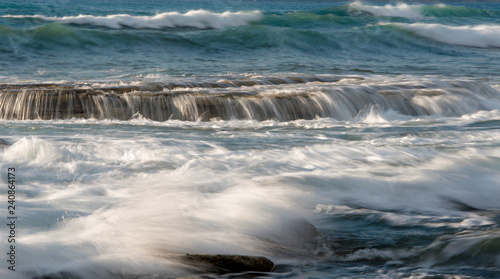Rocky seashore with wavy ocean and waves crashing on the rocks