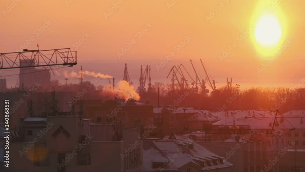 Bright red sunset. Industrial shot. Many hoisting cranes working on the background. A city in smoke Bright red sunset. Industrial shot. Many hoisting cranes working on the background. A city in smoke