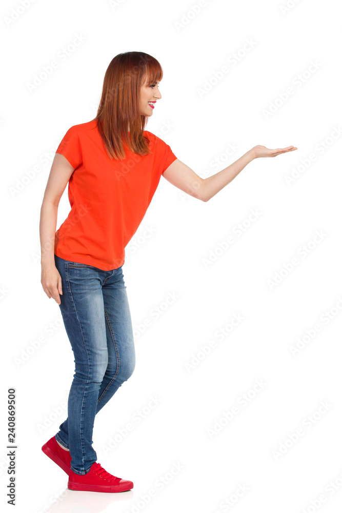 Young Woman Is Holding Something, Looking Away And Smiling. Side View. Young Woman Is Holding Something, Looking Away And Smiling. Side View.