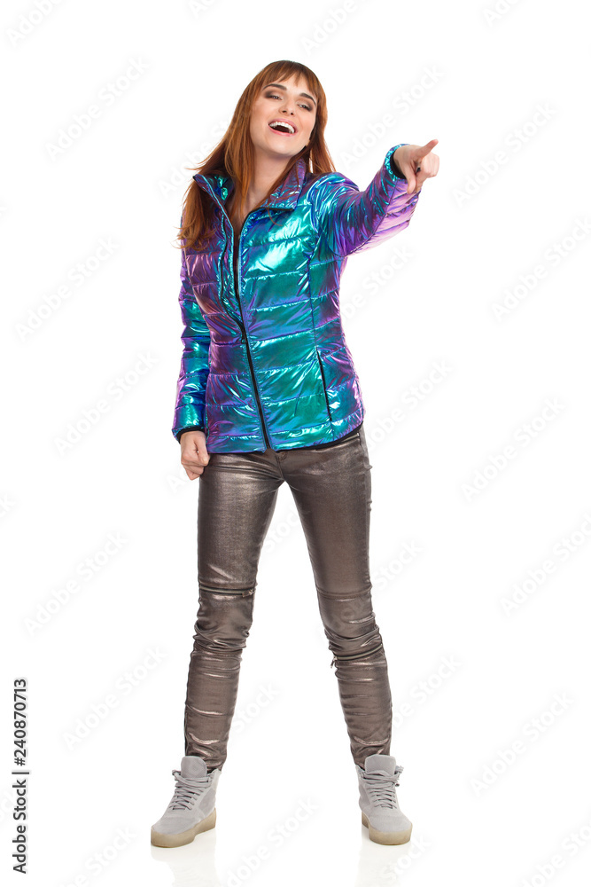 Young Woman In Vibrant Down Jacket Is Pointing And Laughing Young Woman In Vibrant Down Jacket Is Pointing And Laughing