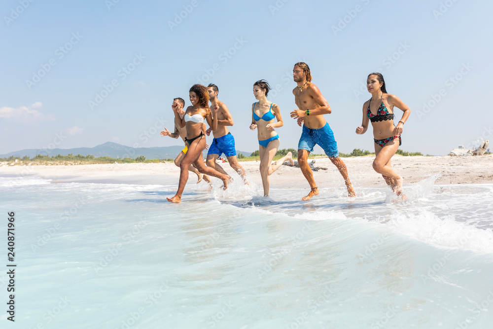 Group of friends having fun on the beach, running into the water Group of friends having fun on the beach, running into the water