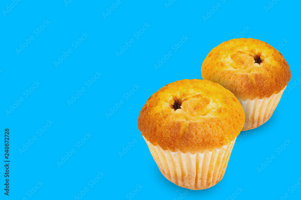 Pair of baked muffins without cream in paper form on blue background with copy space for your text Pair of baked muffins without cream in paper form on blue background with copy space for your text