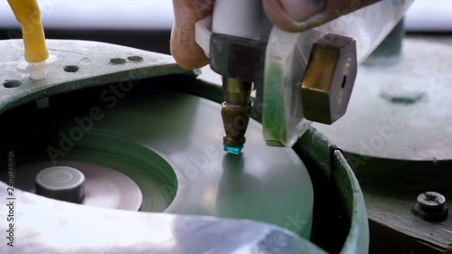 An gemstone cutter polishes a emerald on a faceting machine with chromium oxide in a cutting and polishing workshop. photo