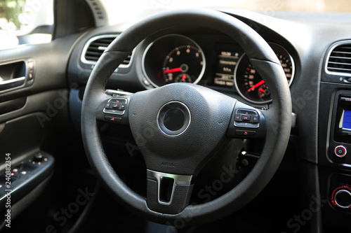 Modern luxury prestige car interior, dashboard, steering wheel. Black perforated leather interior.