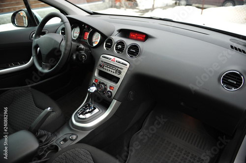 Modern luxury prestige car interior, dashboard, steering wheel. Black perforated leather interior.