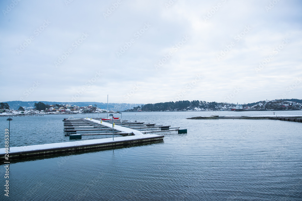 A pier for boats traveling between the Islands around Oslo Norway during the winter overlooking the sea and the Fjord