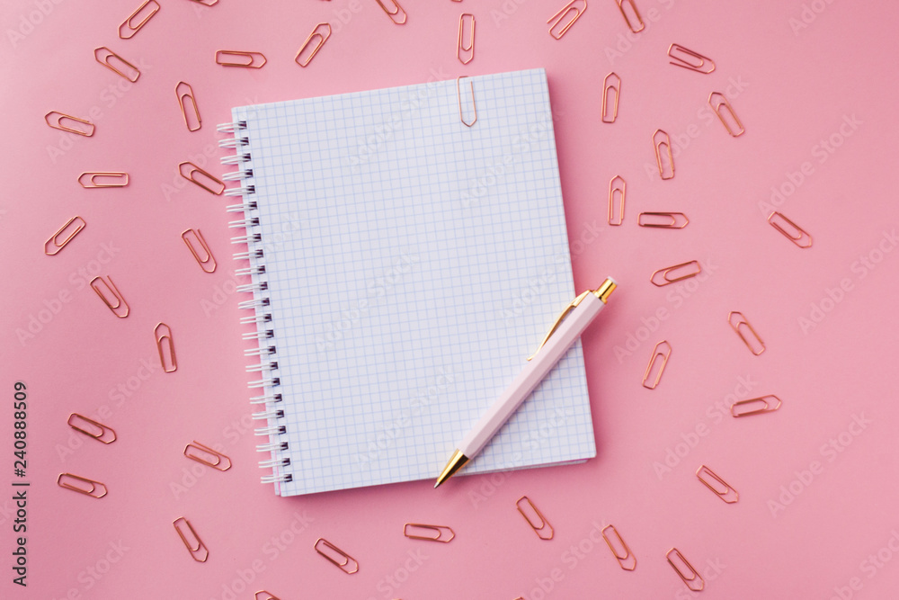 notebook with plastic pink color cover,pen and paper clips. Female set. pink background. selective focus notebook with plastic pink color cover,pen and paper clips. Female set. pink background. selective focus