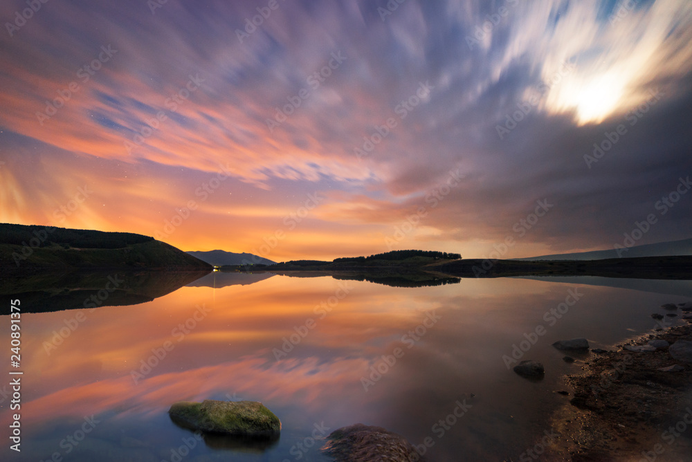 Beautiful moon set on the lake with blue and orange clouds. Night landscape. Beautiful moon set on the lake with blue and orange clouds. Night landscape.