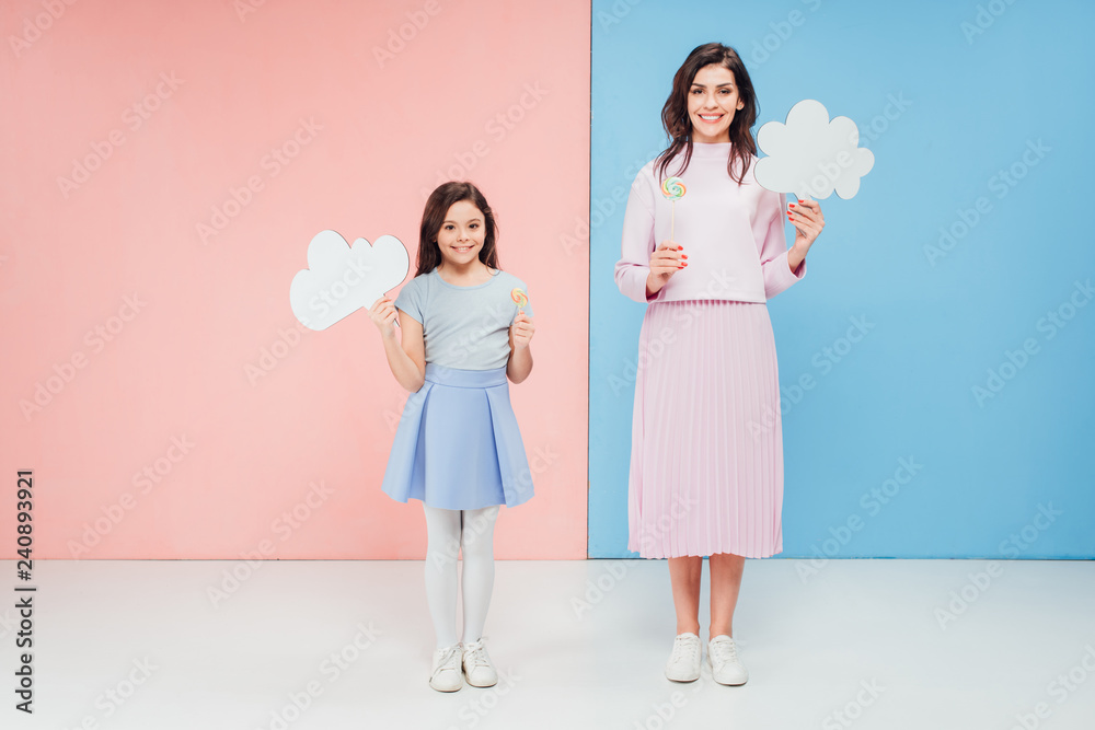 adorable child and attractive woman holding speech bubbles and looking at camera on blue and pink background adorable child and attractive woman holding speech bubbles and looking at camera on blue and pink background